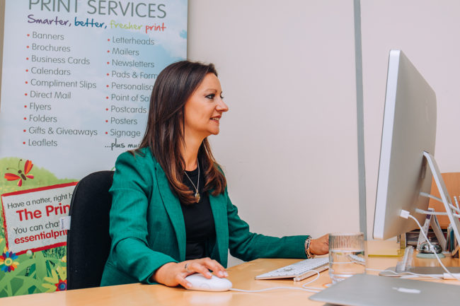 Yvonne Gorman Owner of Essential Print Services Derby Yvonne sits at her desk working