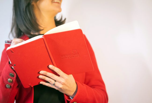 Essential-Print-Services-Notebooks Yvonne is shown holding a branded red notebook with the words Essential Ideas on the front