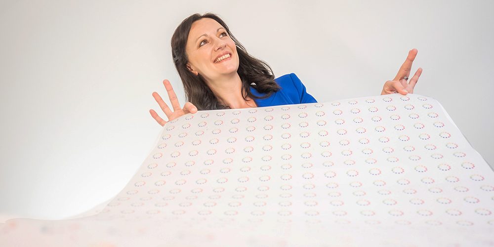 Yvonne Gorman at Derby Essential Print Services Wrapping Paper Yvonne is shown holding a sheet of wrapping paper that has lot of essential print services' logos on it