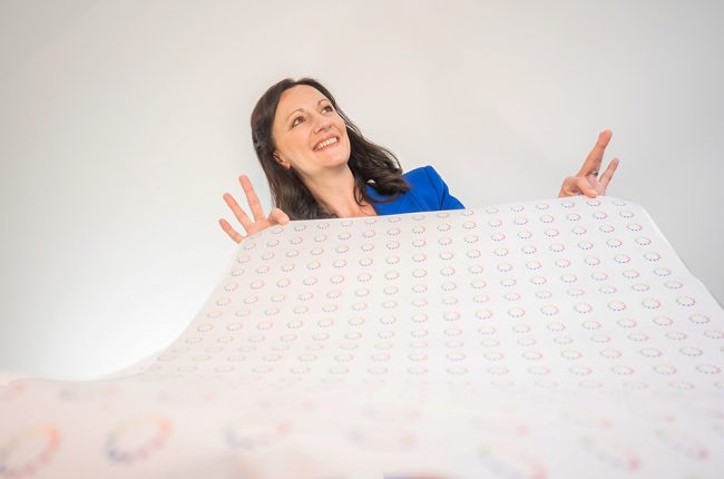 Yvonne Gorman at Derby Essential Print Services Wrapping Paper Yvonne is shown holding a sheet of wrapping paper that has lot of essential print services' logos on it